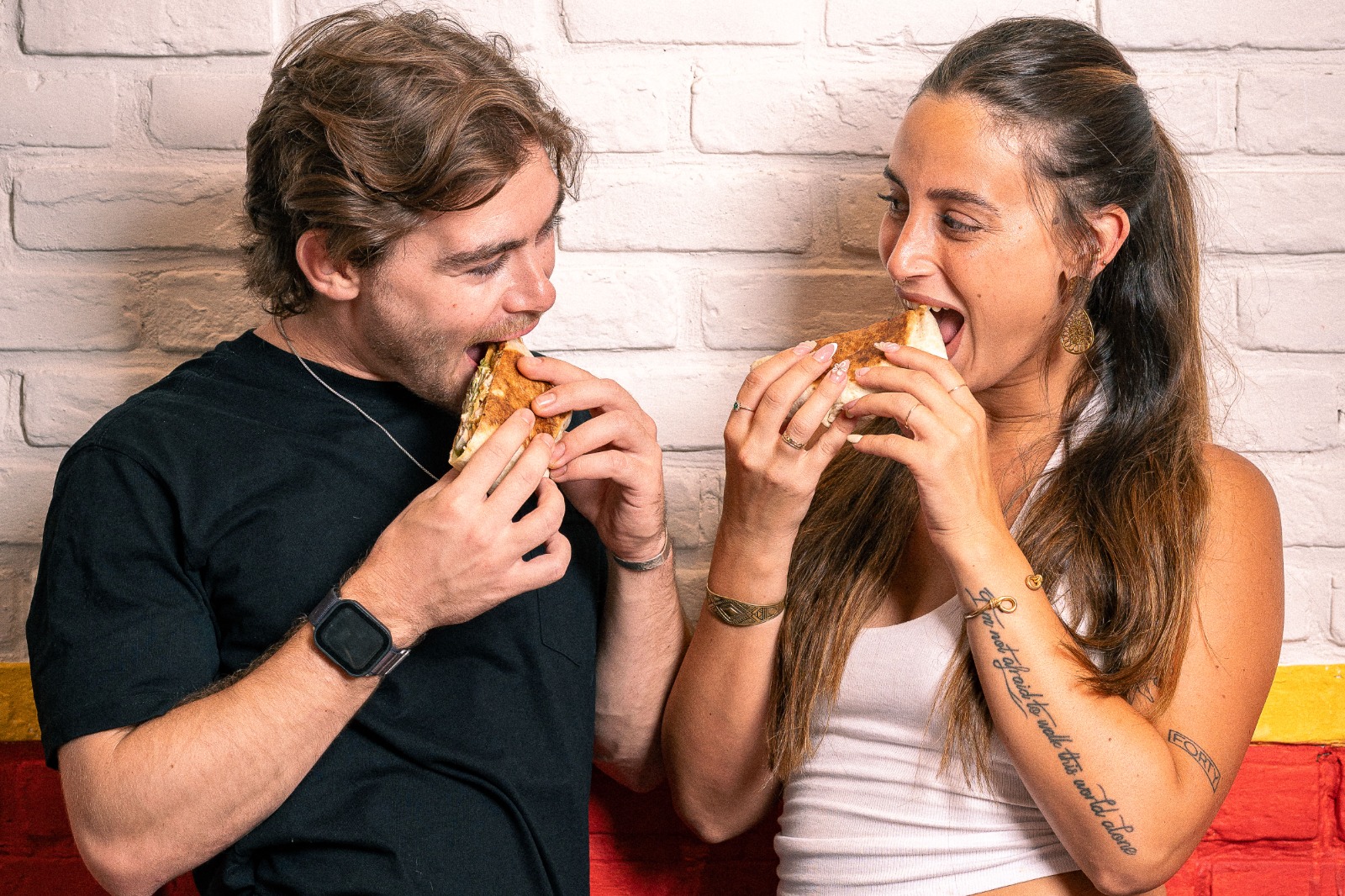 בחור ובחורה נוגסים ברפידוס כשהם מסתכלים אחד על השניה